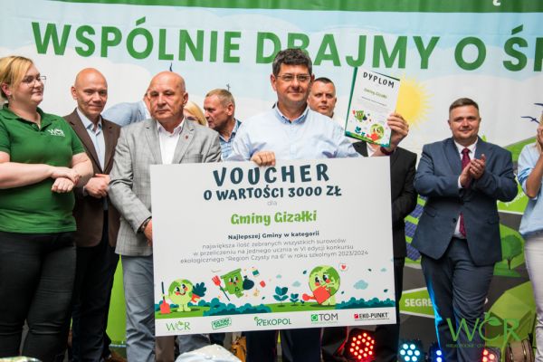 Wójt gminy odbiera dyplom i voucher