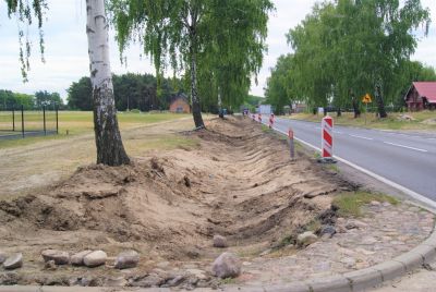 Rozkopane pobocze, drzewa, oznakowanie robót drogowych