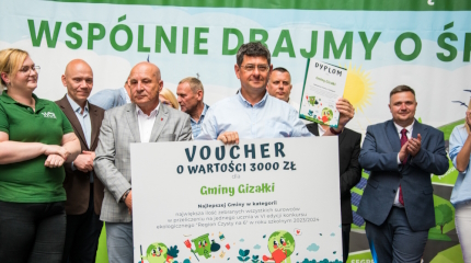 Wójt gminy odbiera dyplom i voucher